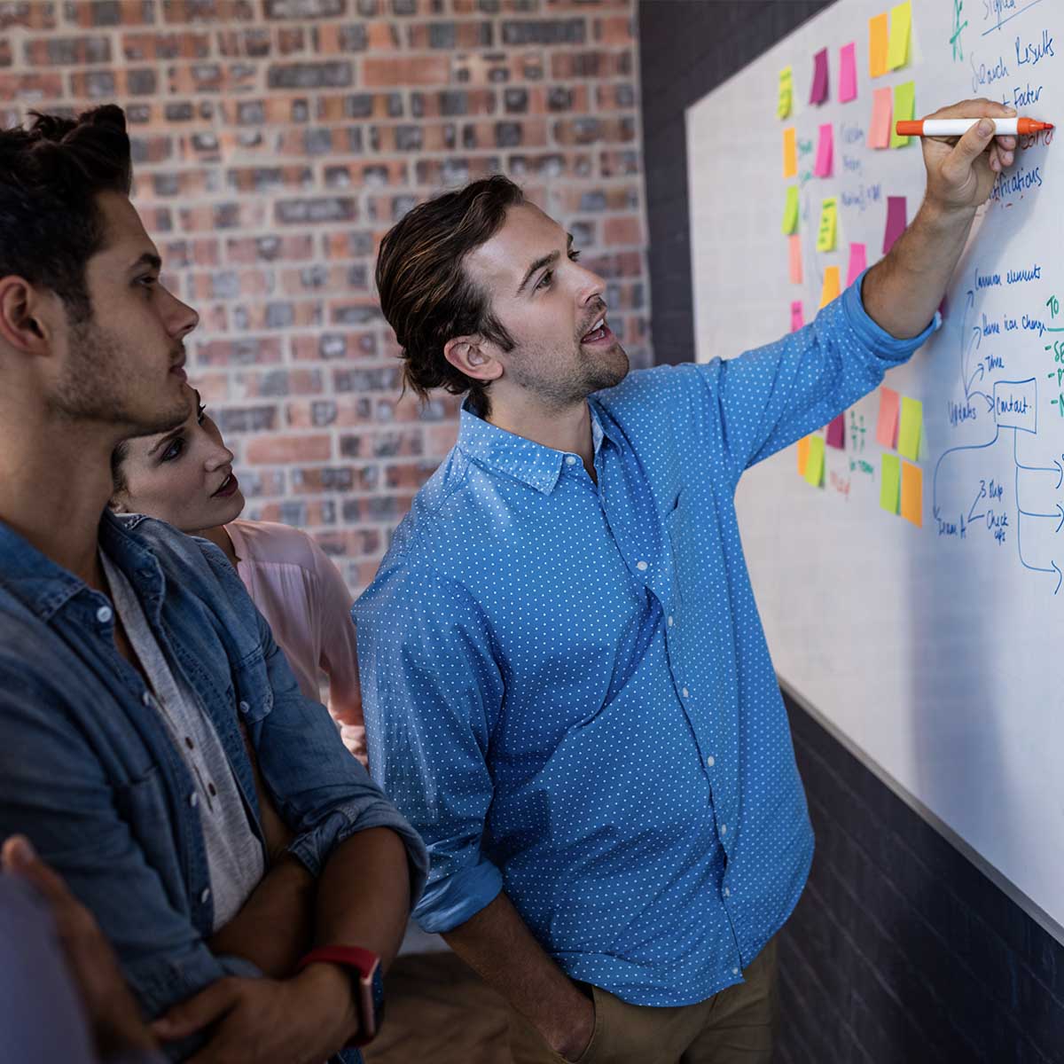 Coworkers interacting front of a board in the office