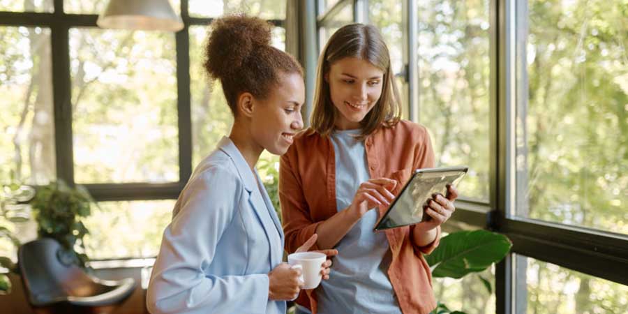 woman showing something on a tablet to another woman