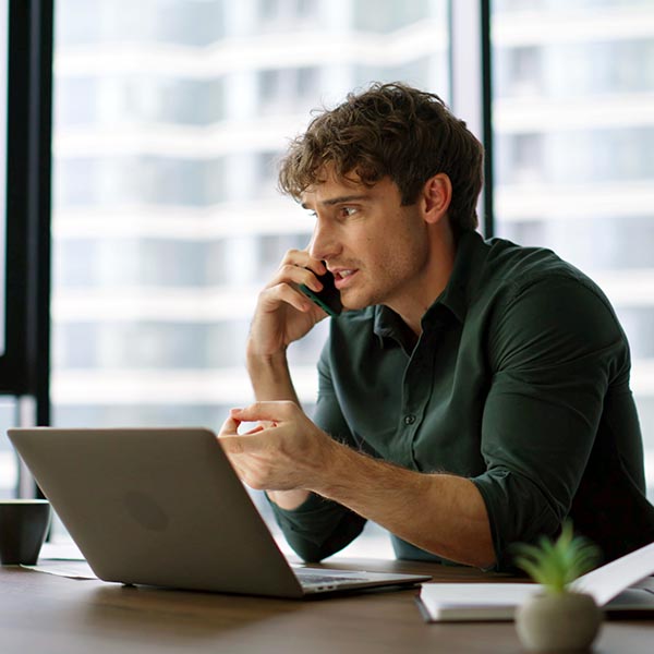 Professional on a phone call at a laptop in an office