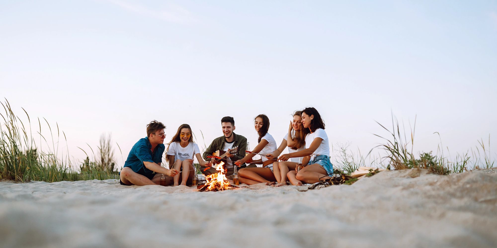 group of people around the bonfire on a beach