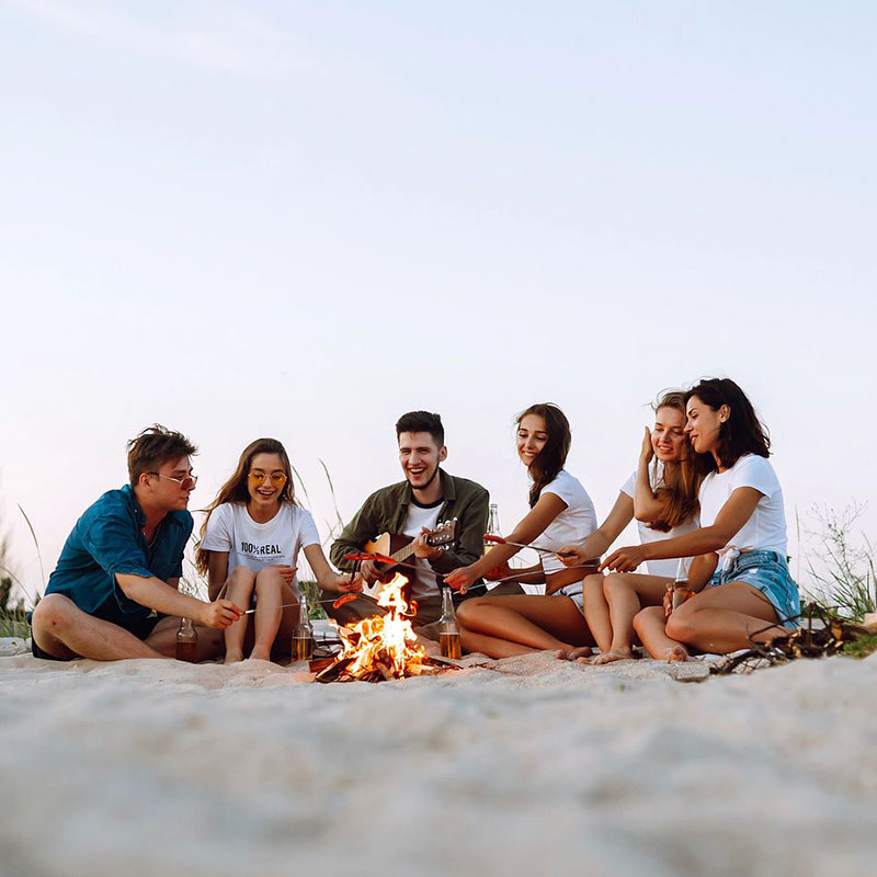 group of people around the bonfire on a beach
