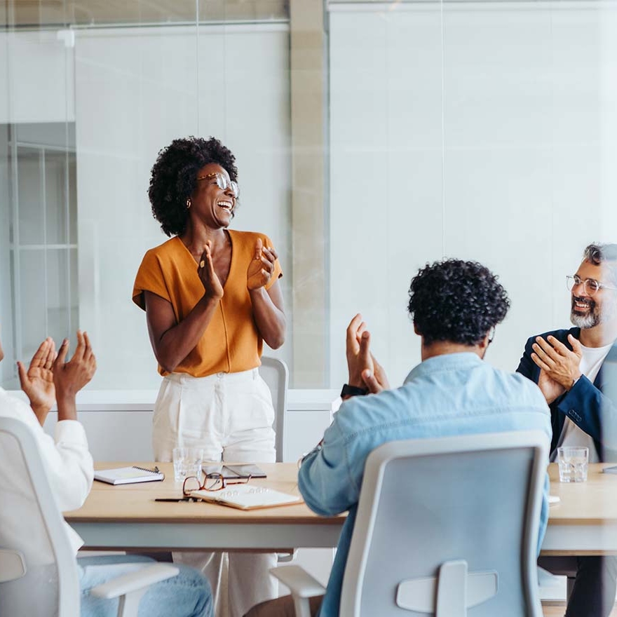 Team members applauding during a meeting in a modern office