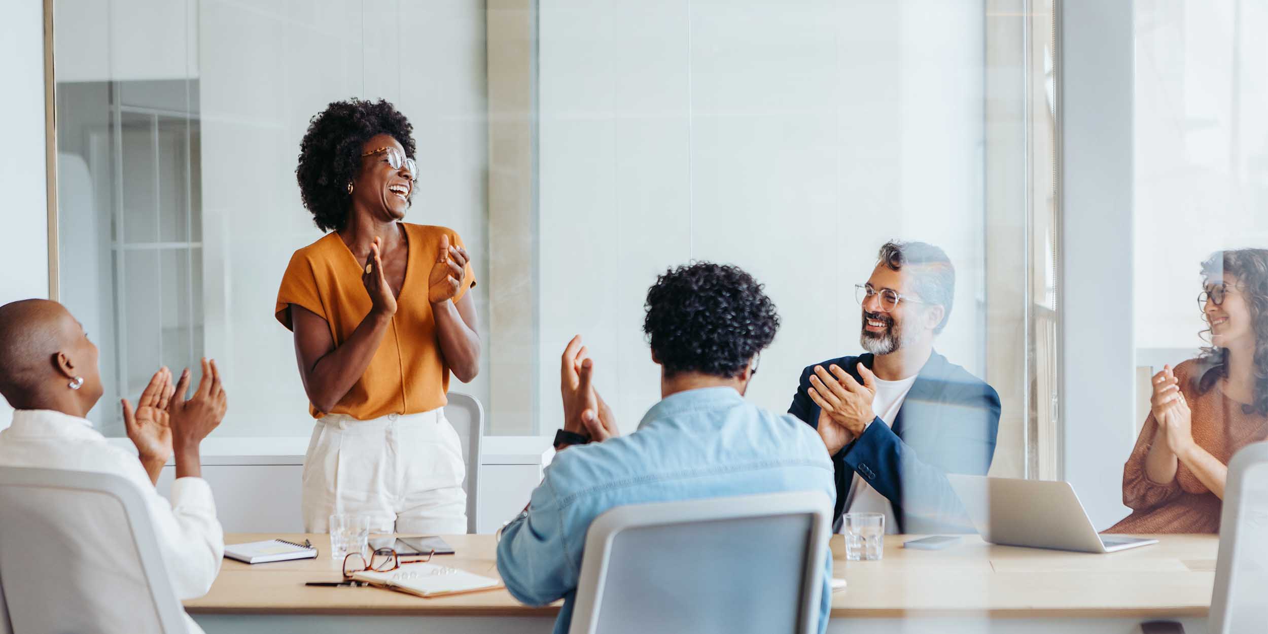 Team members applauding during a meeting in a modern office