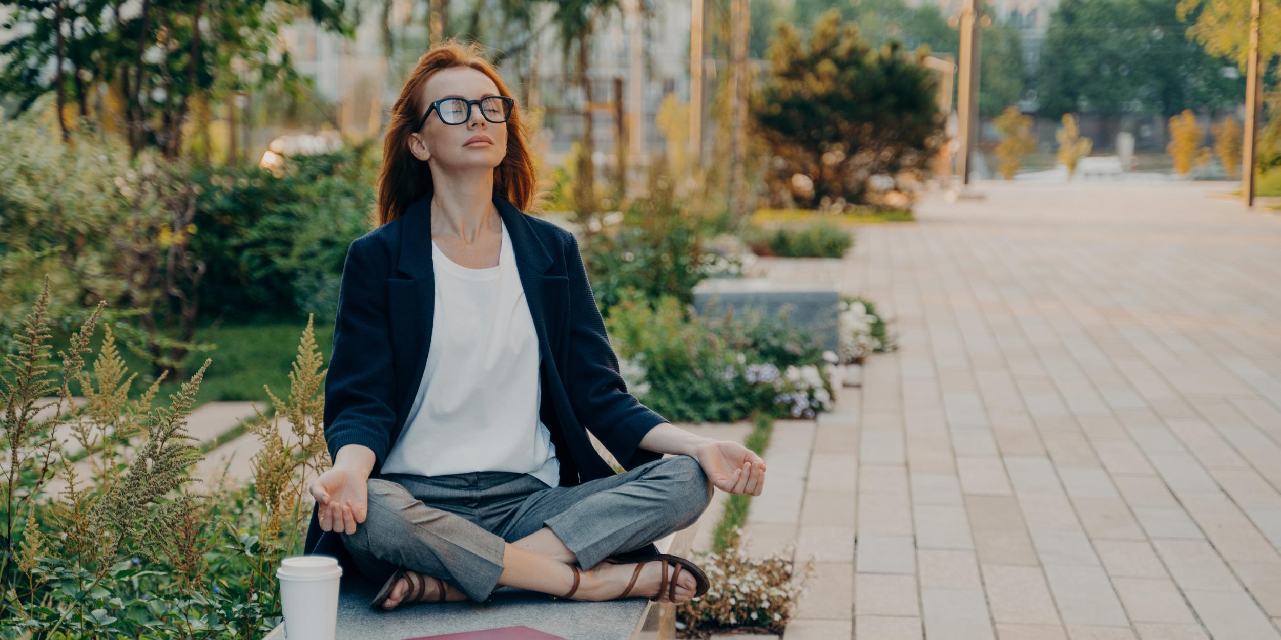 person meditating outdoors in business attire