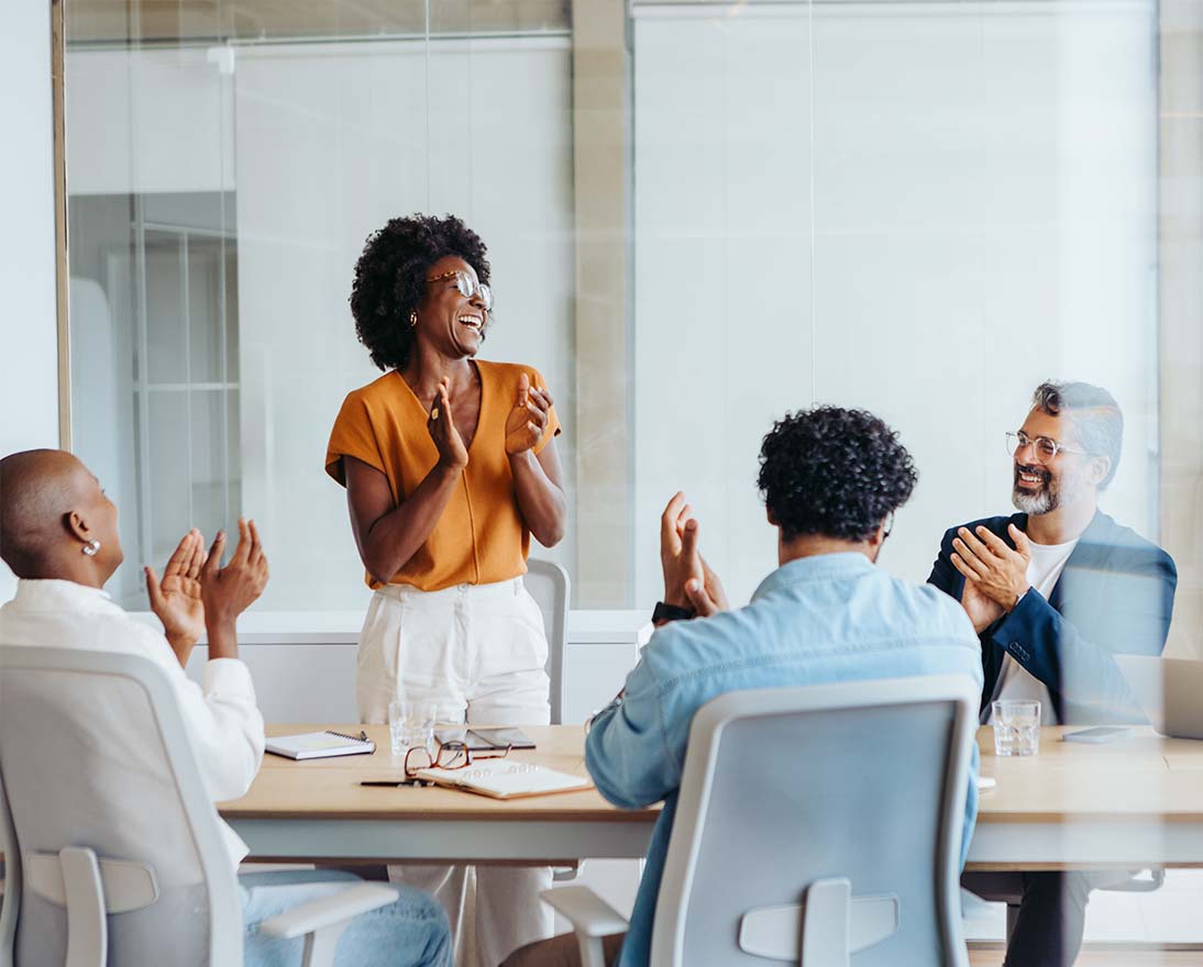 Team members applauding during a meeting in a modern office