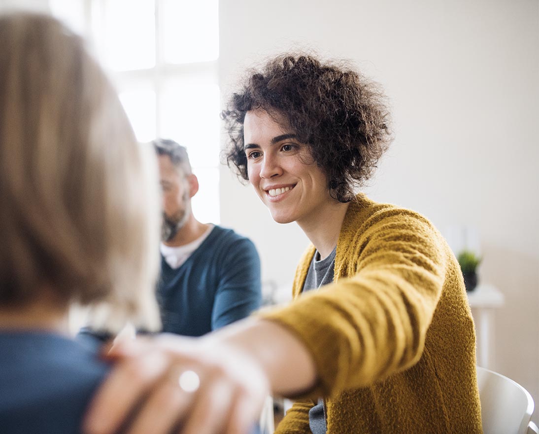 woman is putting her hand supportive on other woman's shoulder