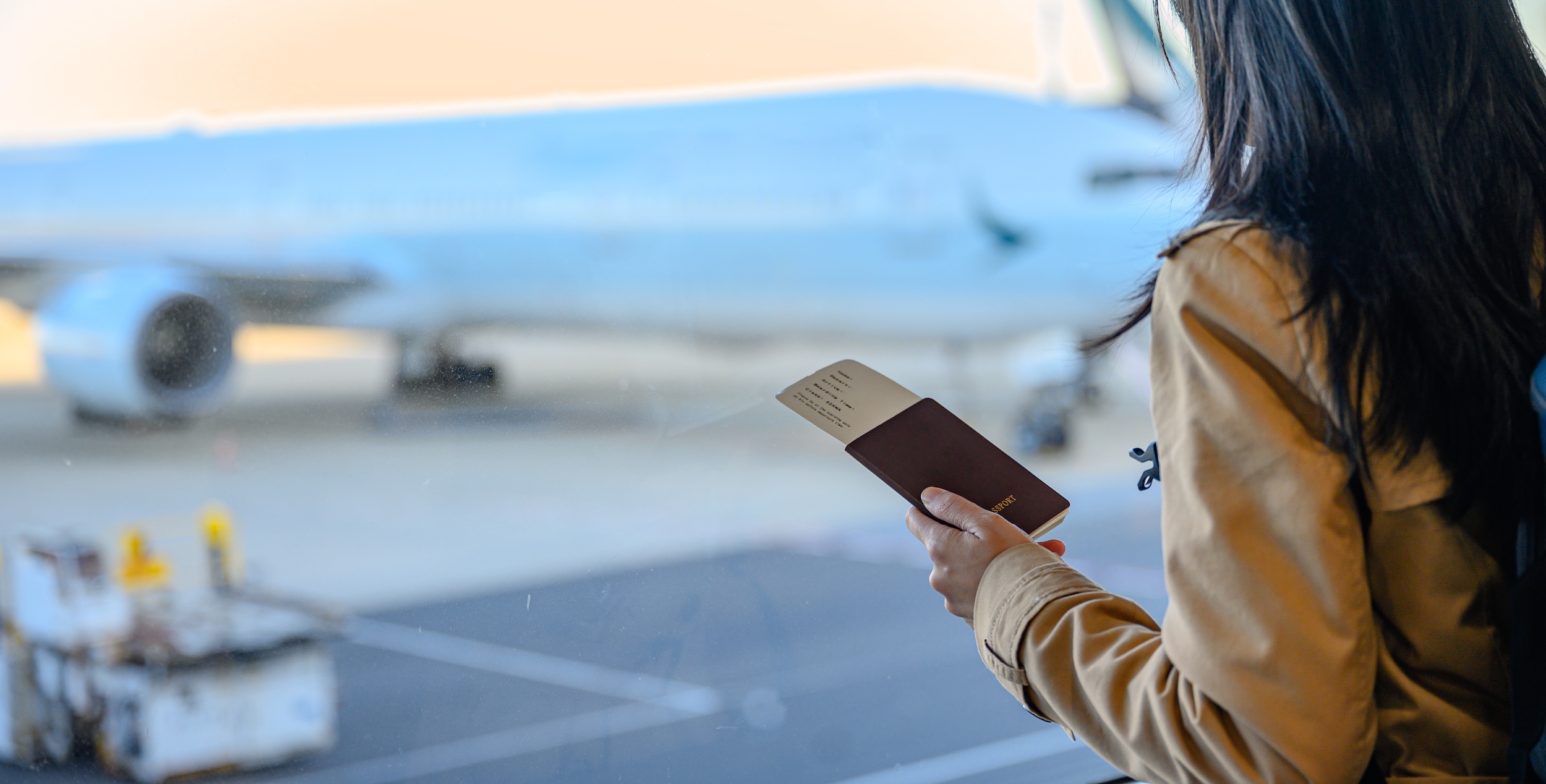 Woman holding passport looking at airplane