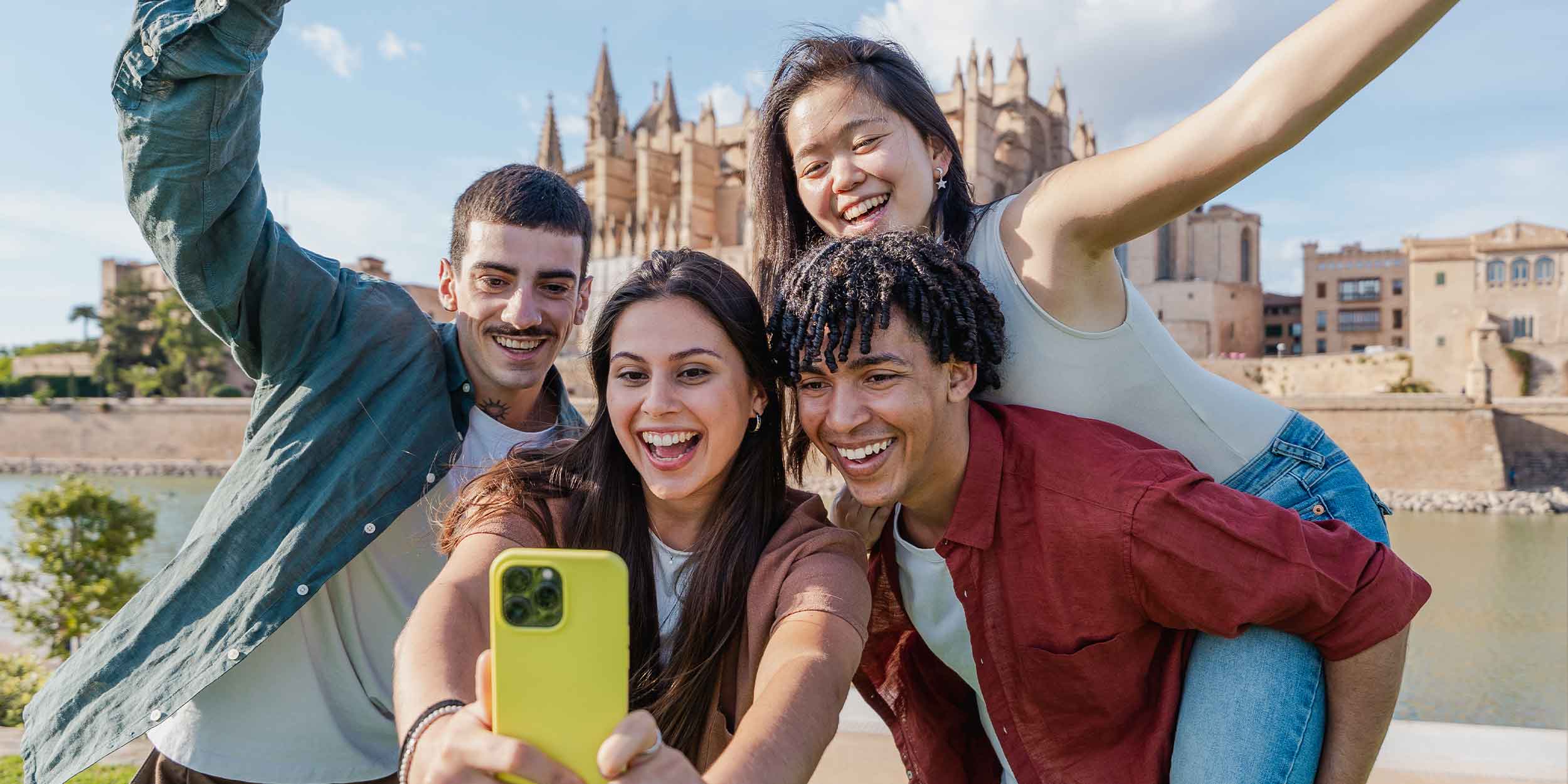 Smiling multiethnic group of young friends taking a fun selfie near a cathedral