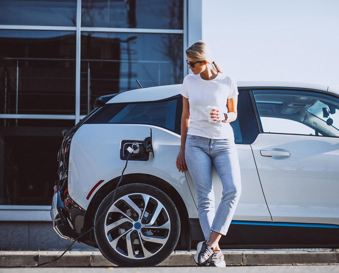 Young woman recharging battery for electric car