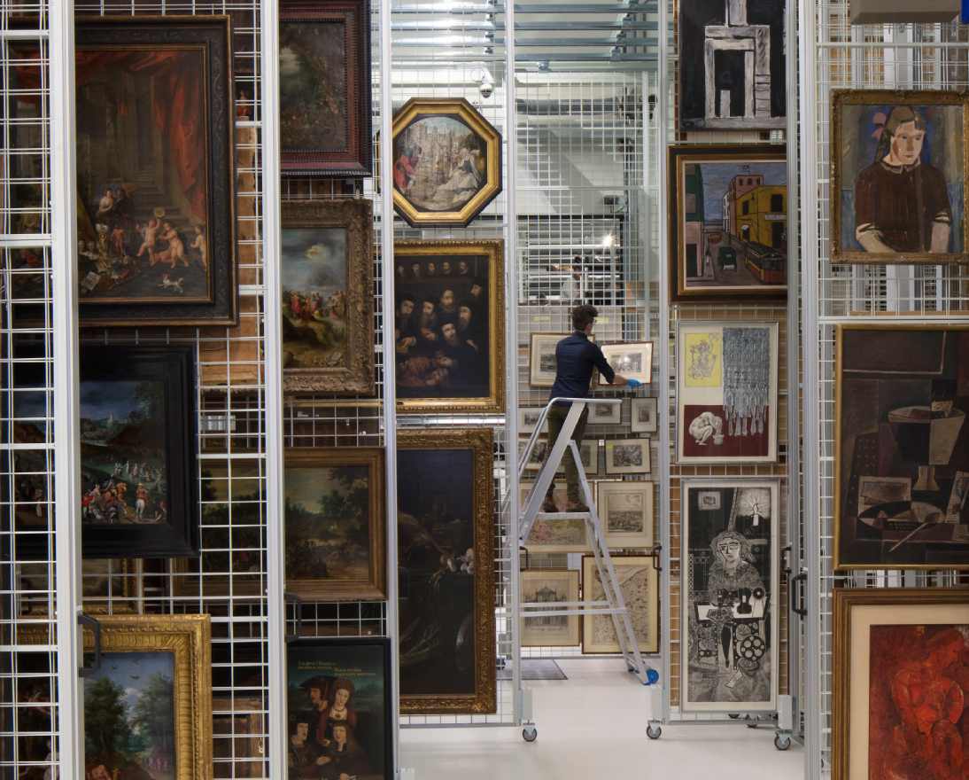 Person organizing paintings in an art storage facility.