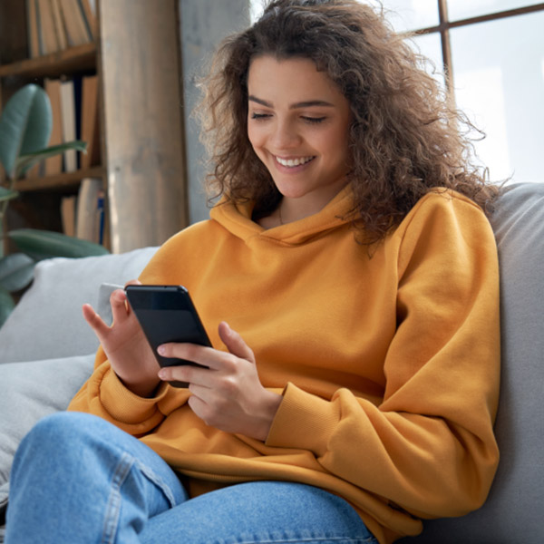Person using a smartphone while relaxing at home on a sofa