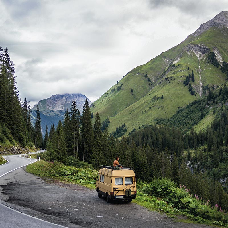 camper van in the forest mountain road in the mountains