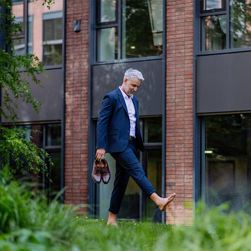 Businessman walking barefoot in park