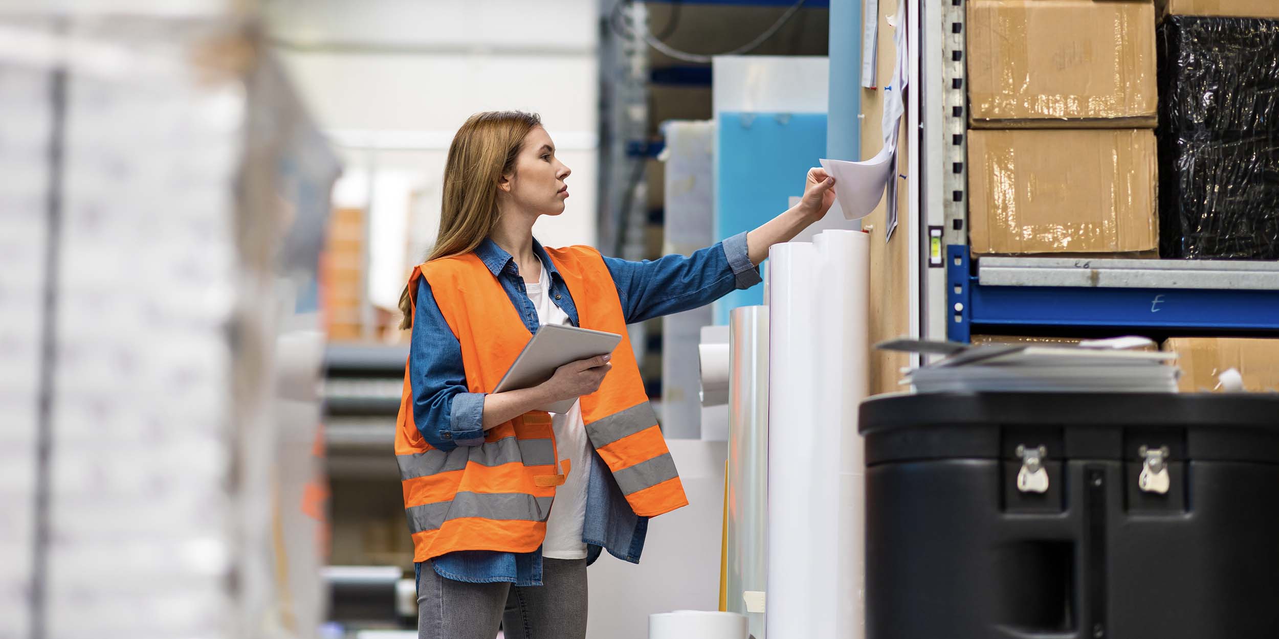 Woman with tablet in factory storehouse checking location of goods