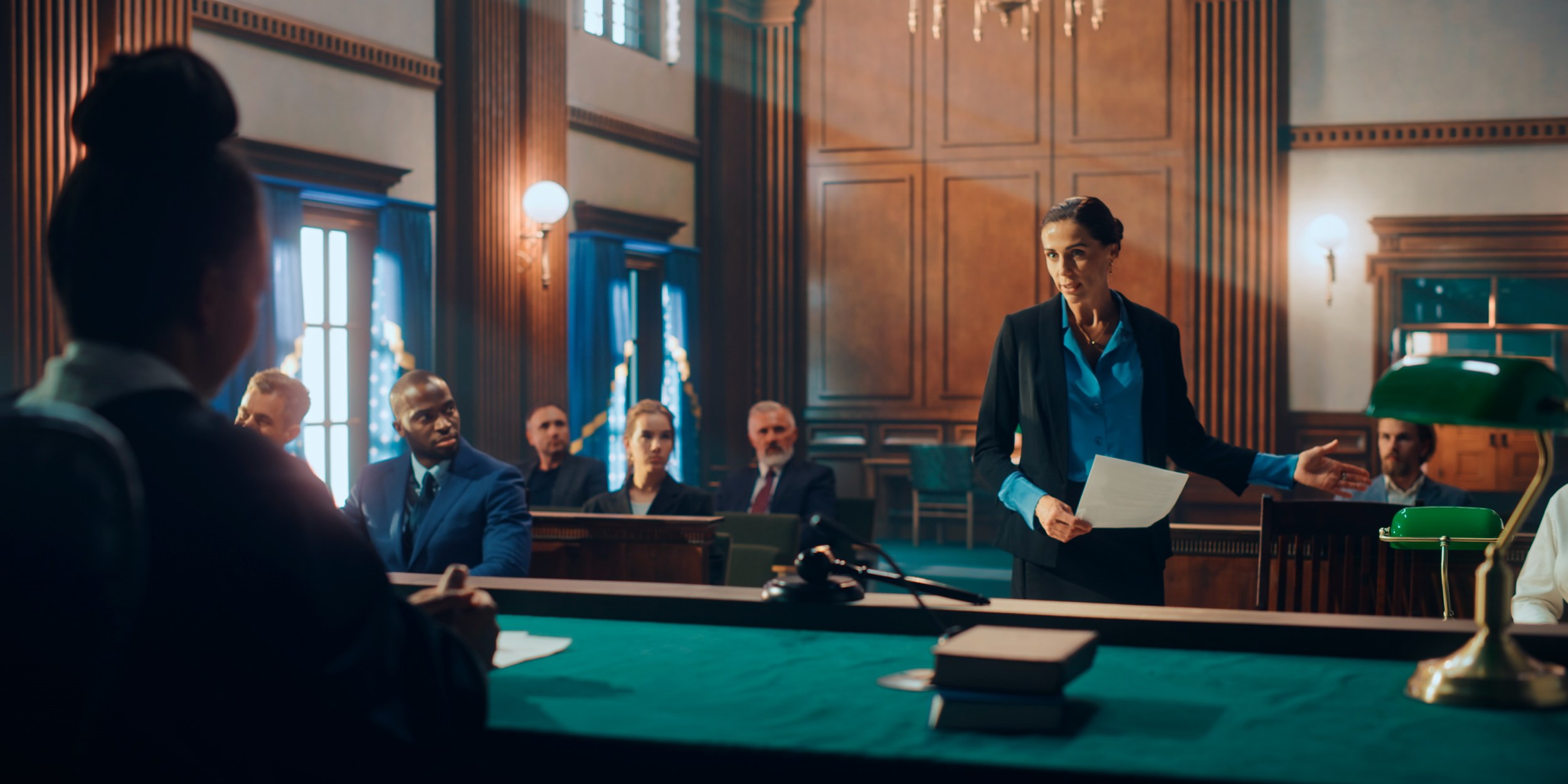 Lawyer presenting documents in a courtroom with judge and audience during trial proceedings.