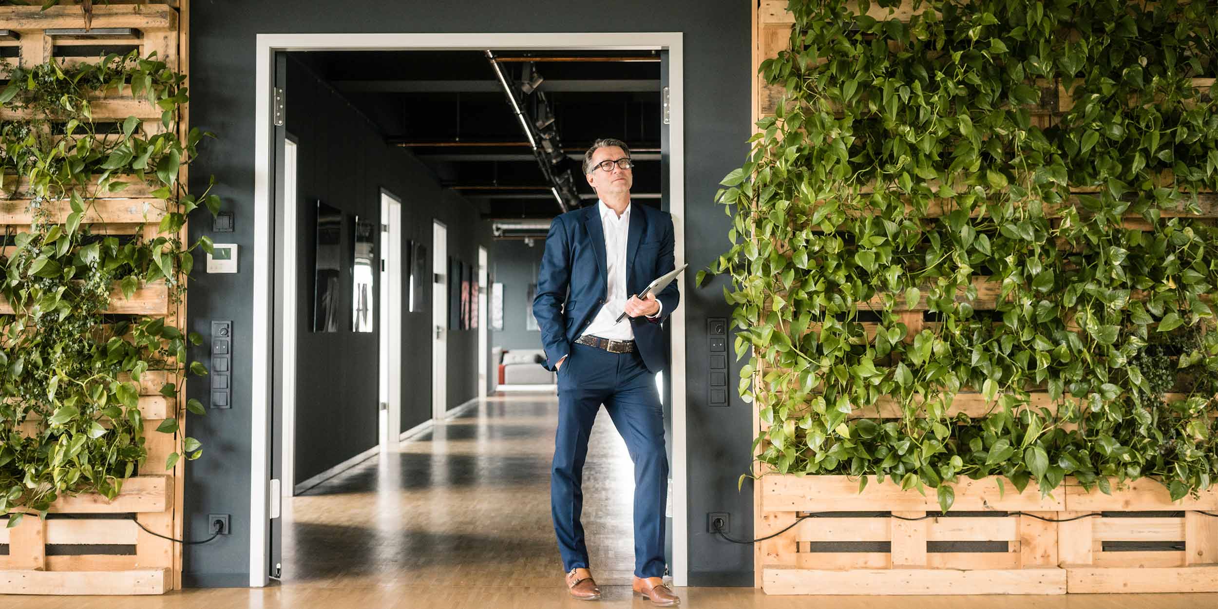 man standing next to wall with plants