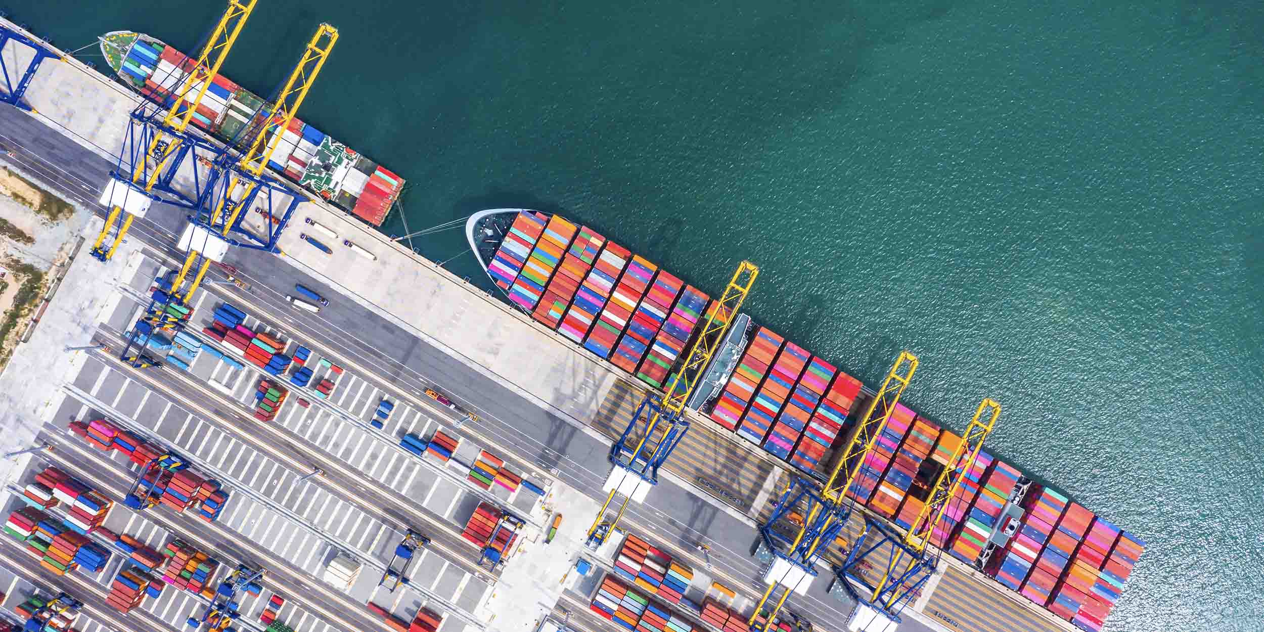Aerial view of a busy container port handling cargo ships and shipping containers.