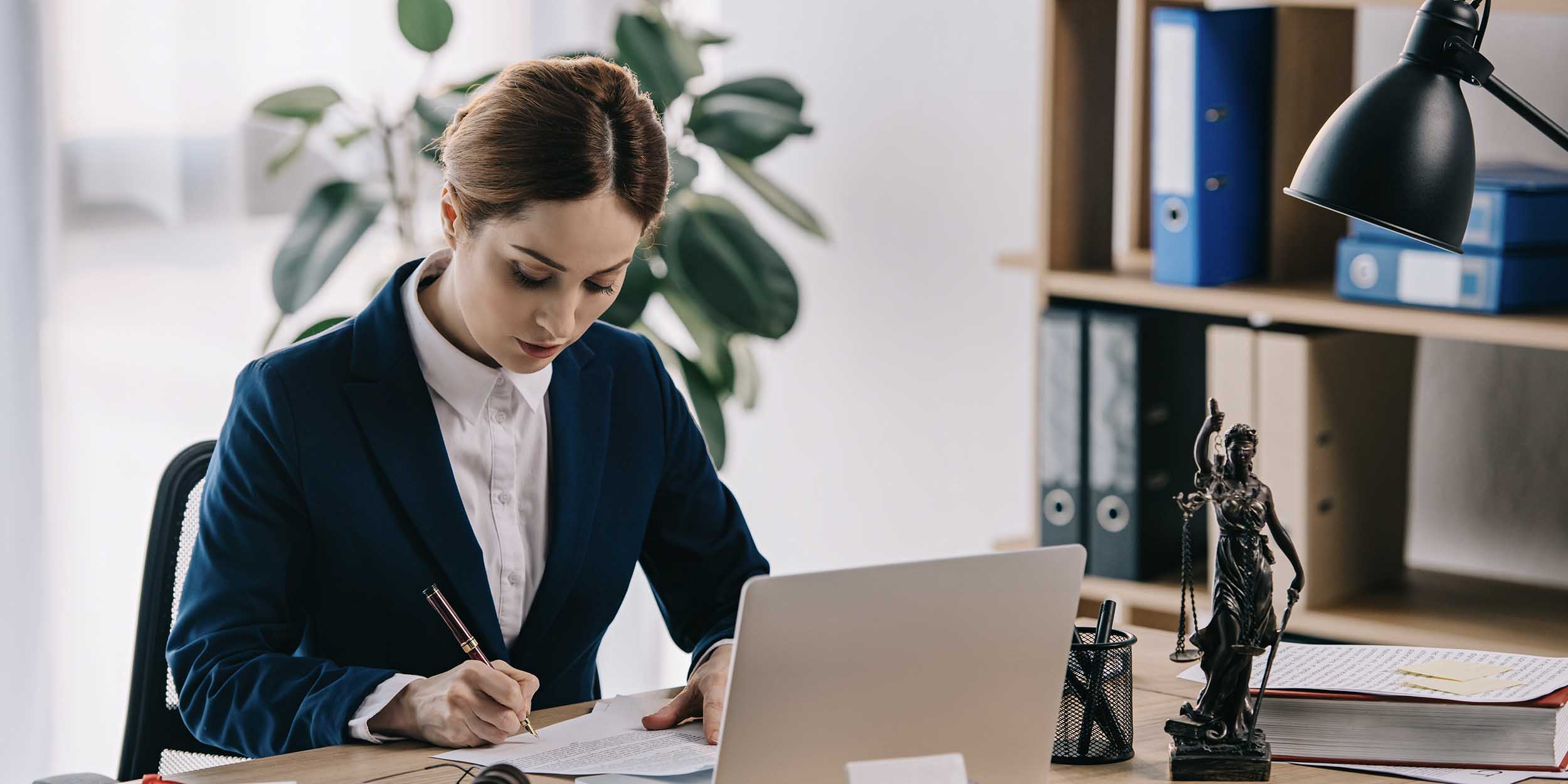 female lawyer in suit at workplace with laptop