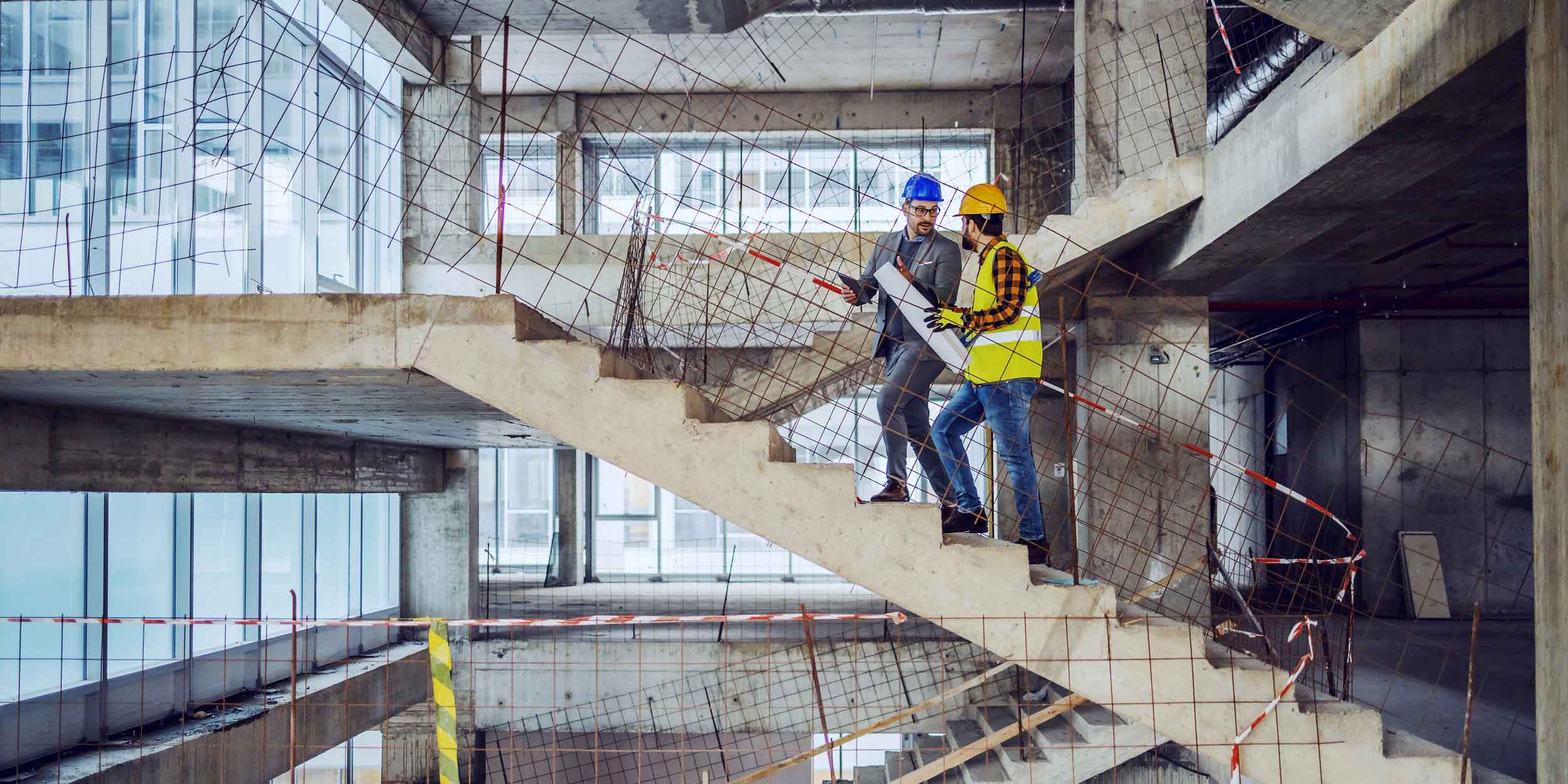 Construction worker and main architect climbing the stairs and talking about progress