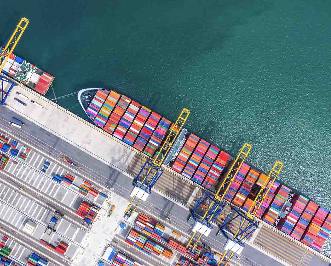 Aerial view of a busy container port handling cargo ships and shipping containers.