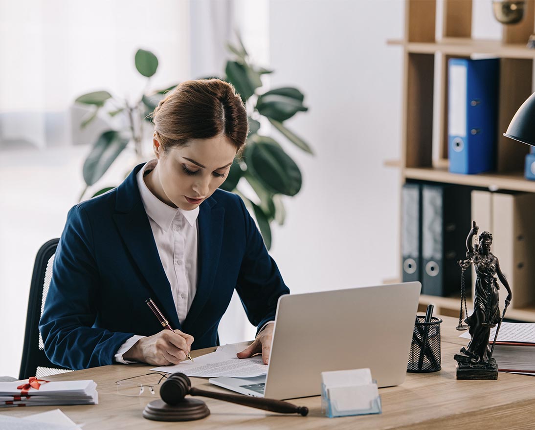 female lawyer in suit at workplace with laptop