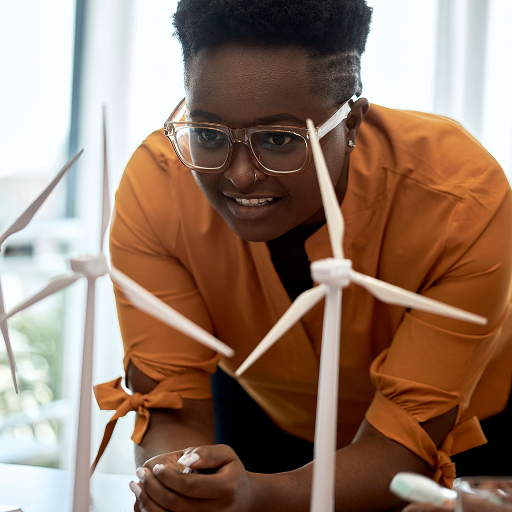 Woman wearing eyeglasses examining wind turbine models at office
