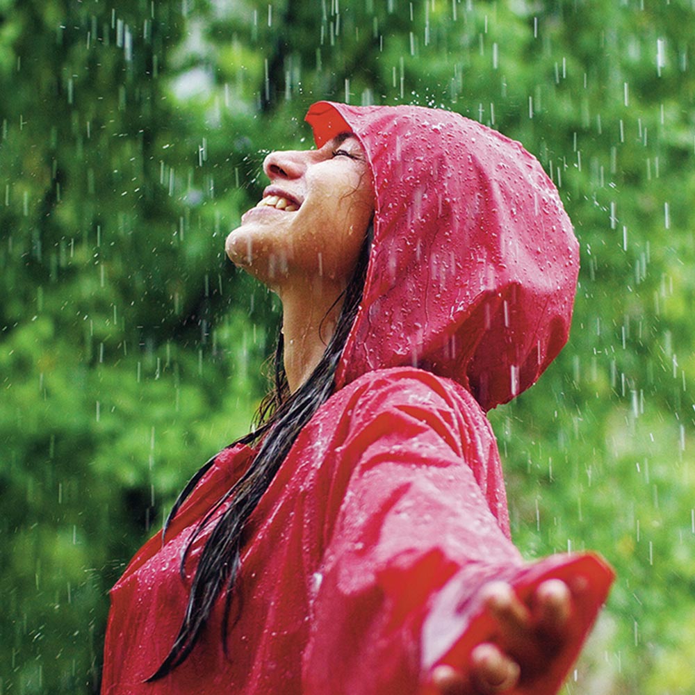 young woman smiles and laughs under the rain