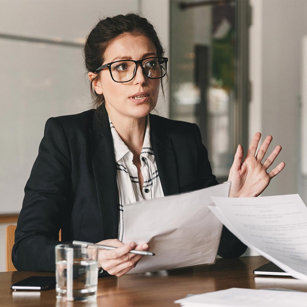 two women talking while holding documents
