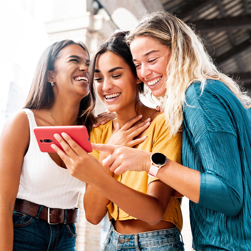 three women looking at a phone together