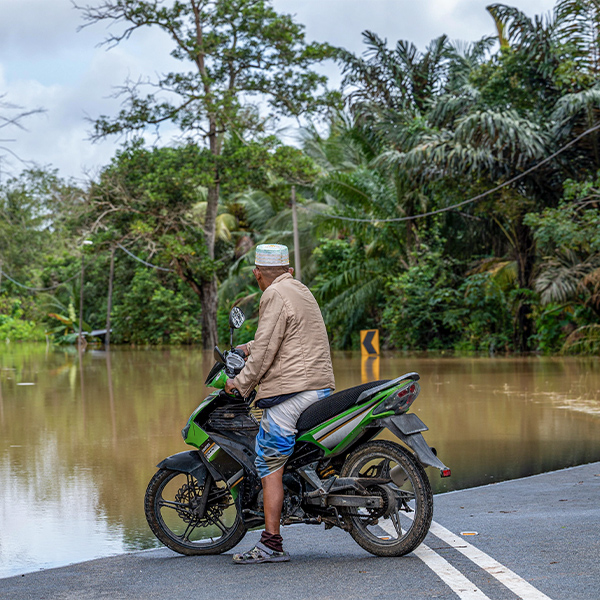 man on a motorcycle looking at a flood