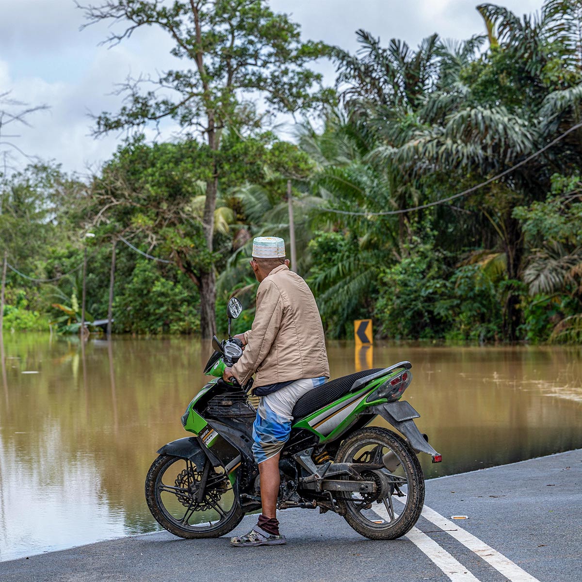 man on a motorcycle looking at a flood 
