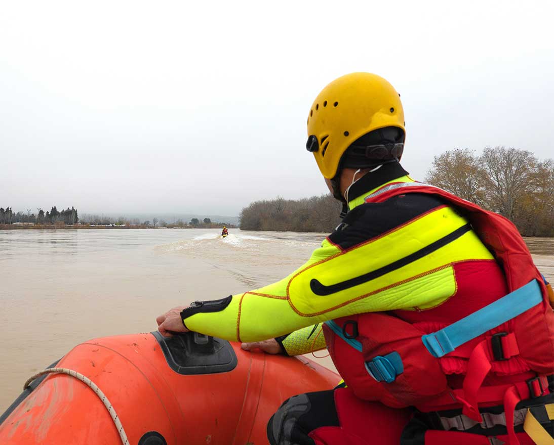 rescuer watches the river during a flood while riding in a boat