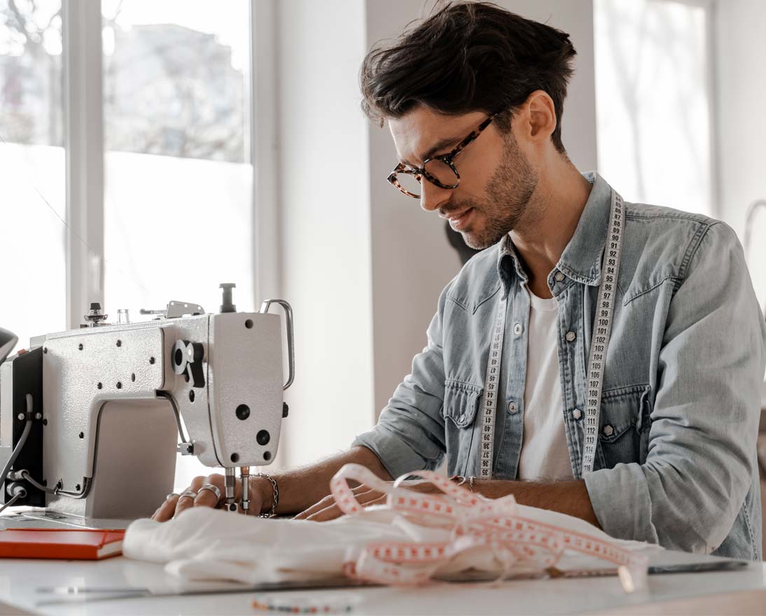 Young man sews at a sewing machine