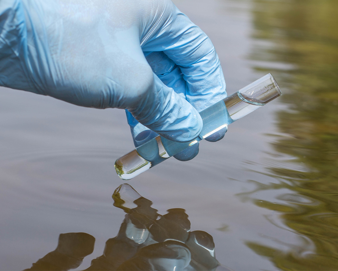 Hand in glove takes a sample of water from the river for analysis
