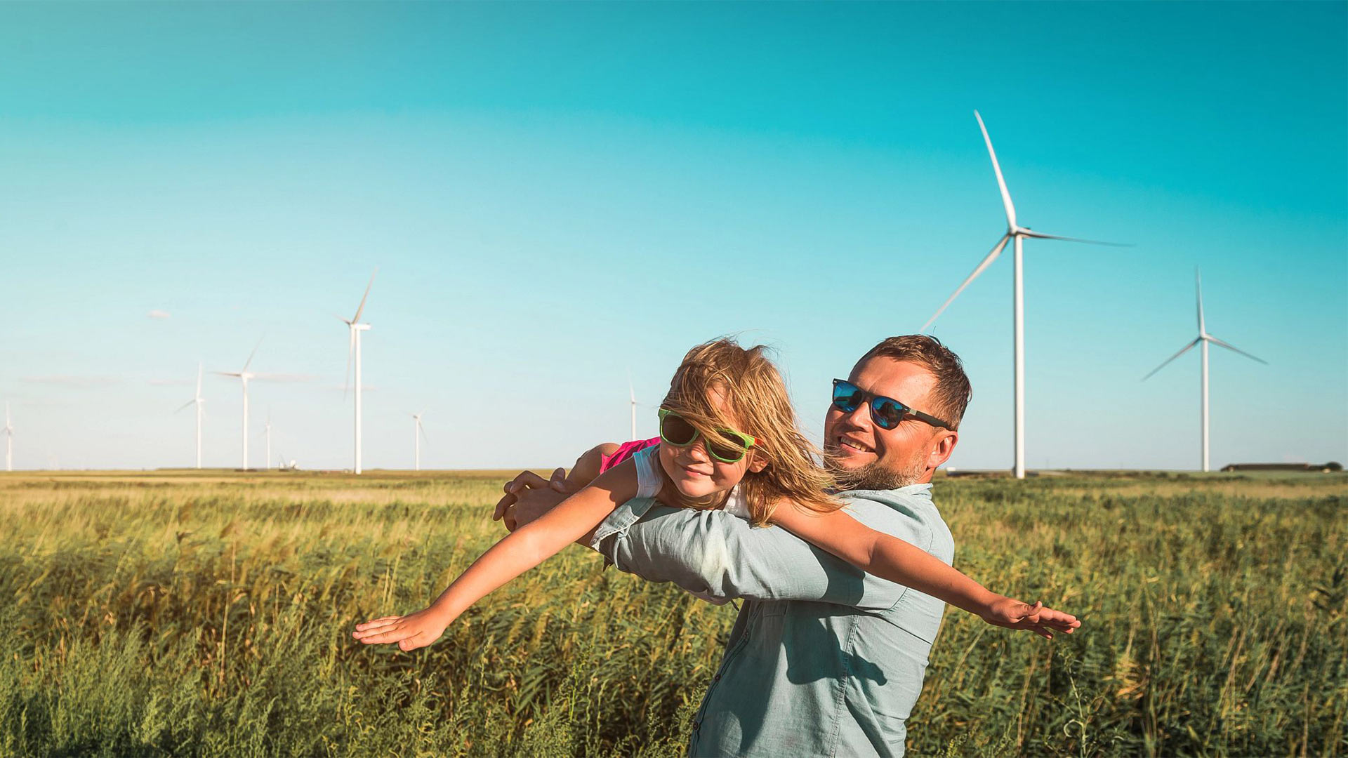 father and daughter playing in front of windmills