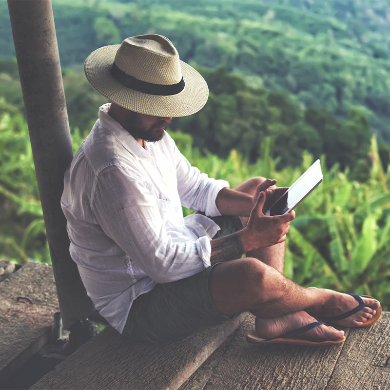 a man working on his tablet with a view on a forest