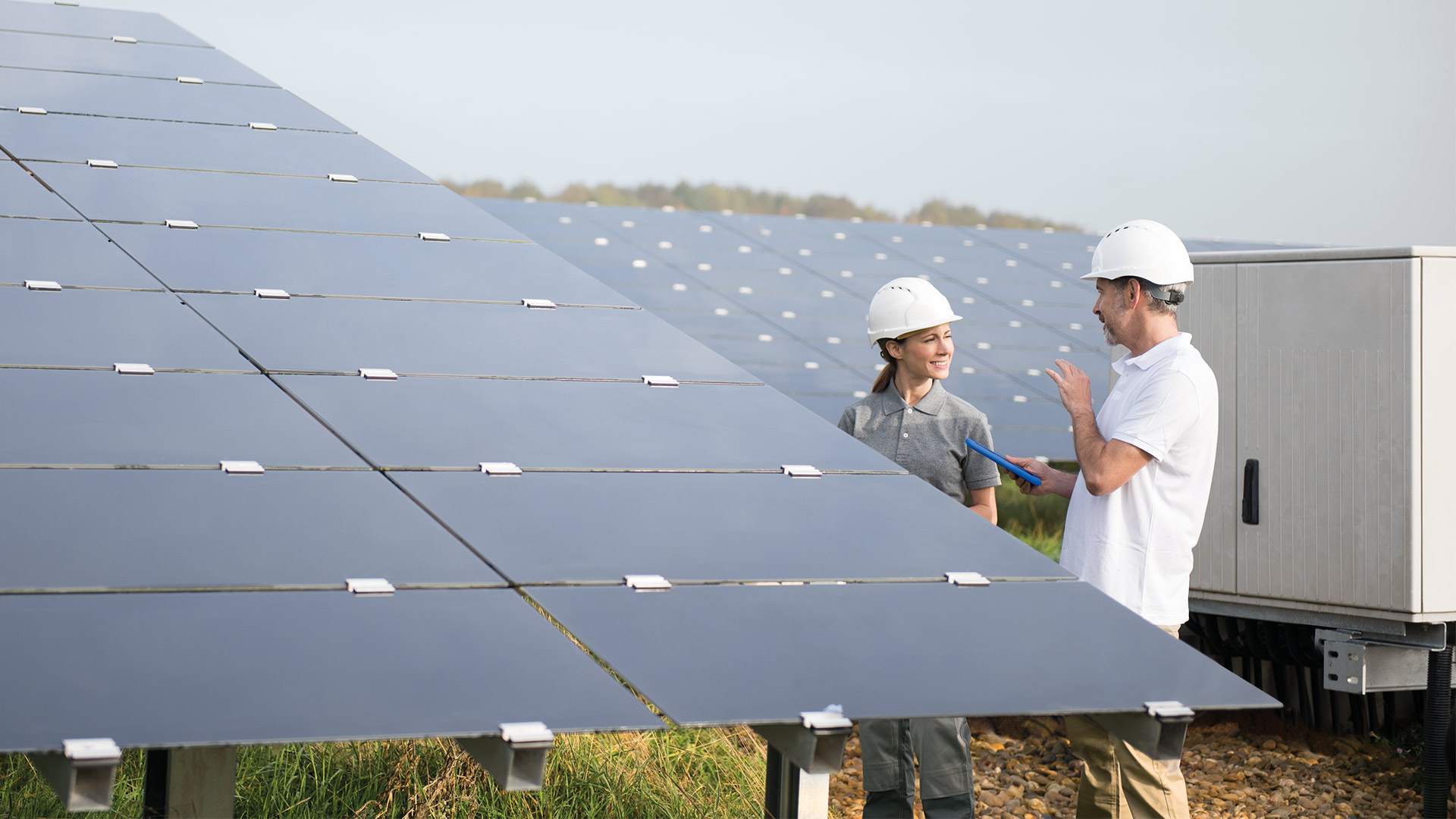 two people standing next to solar panels